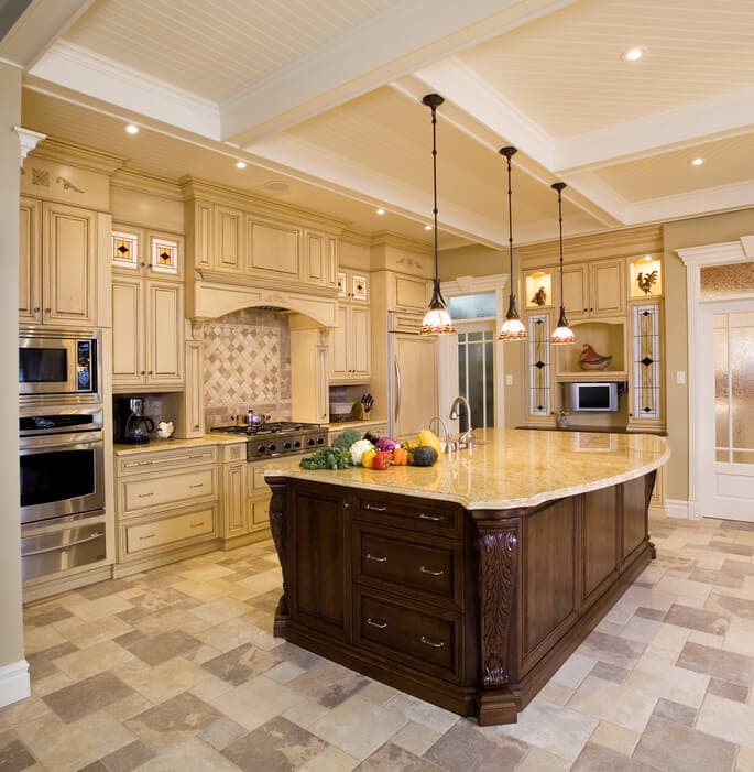 Kitchen with cream cabinetry, a dark wood island and a stone countertop under pendant lights